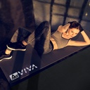 Woman doing ab training on the AsVIVA floor protection mat UM2 in a dark studio
